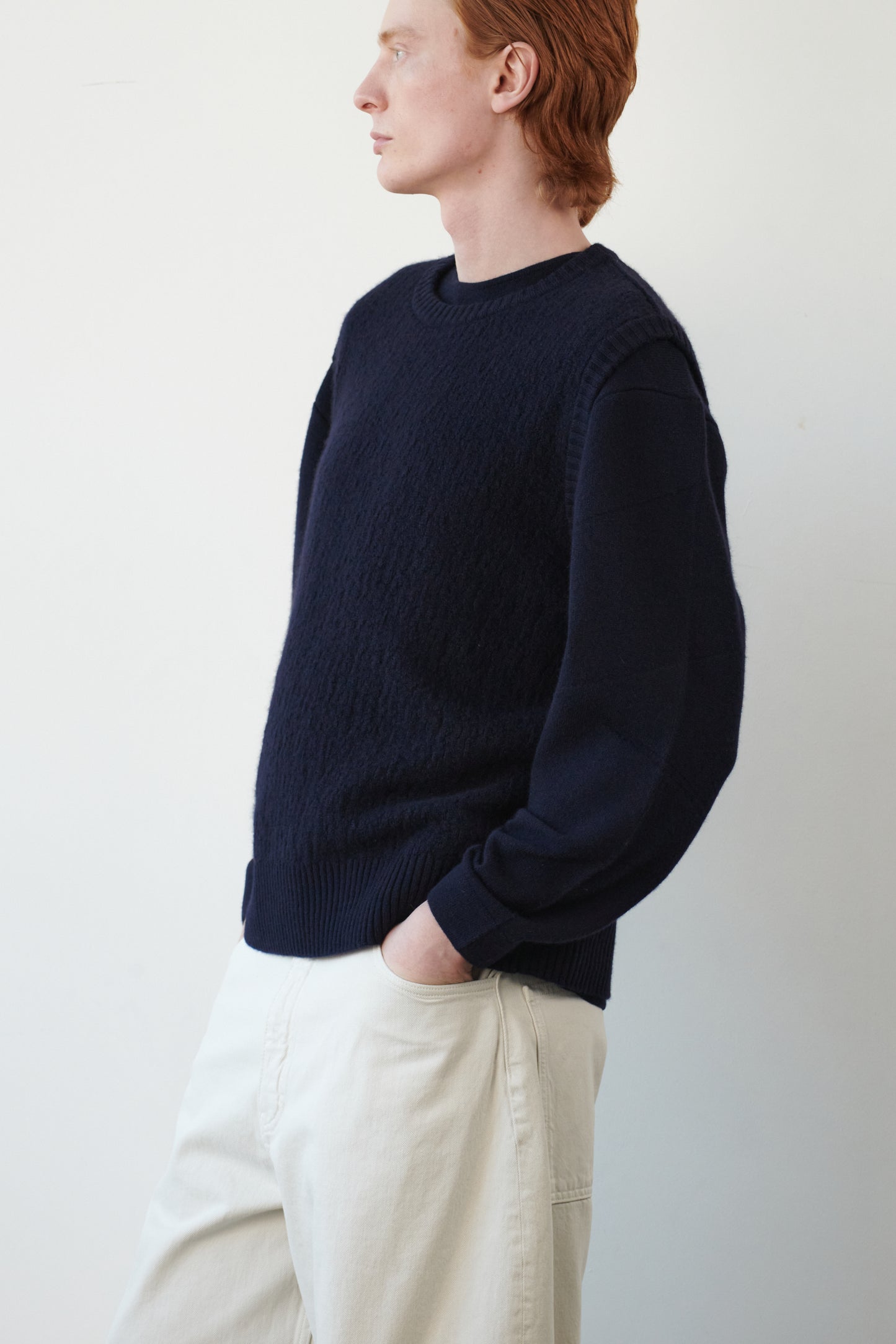 This image features the Terra Top, a stylish knitted texture vest crafted from 100% cashmere, providing an unmatched softness and warmth. The model is seen wearing the vest showcasing the vest's sophisticated and subtle textured design.