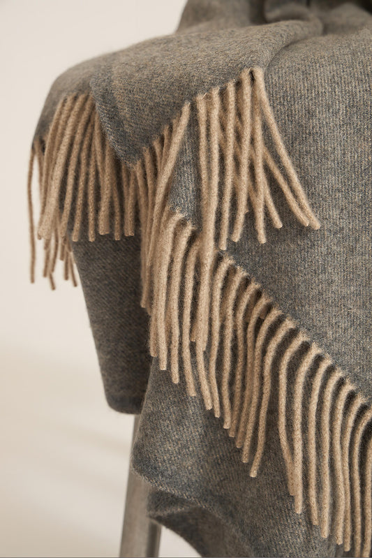 A slate grey cashmere throw with fringes at the top and bottom edges, displayed on a plain background.