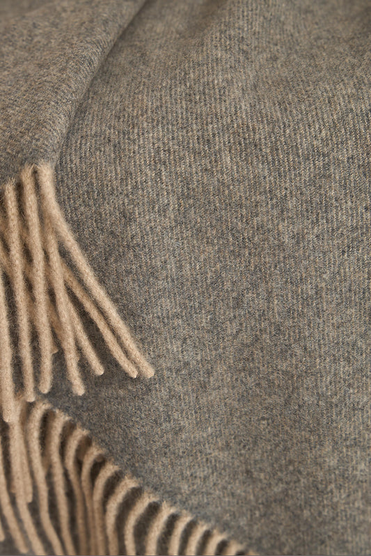 A slate grey cashmere throw with fringes at the top and bottom edges, displayed on a plain background.