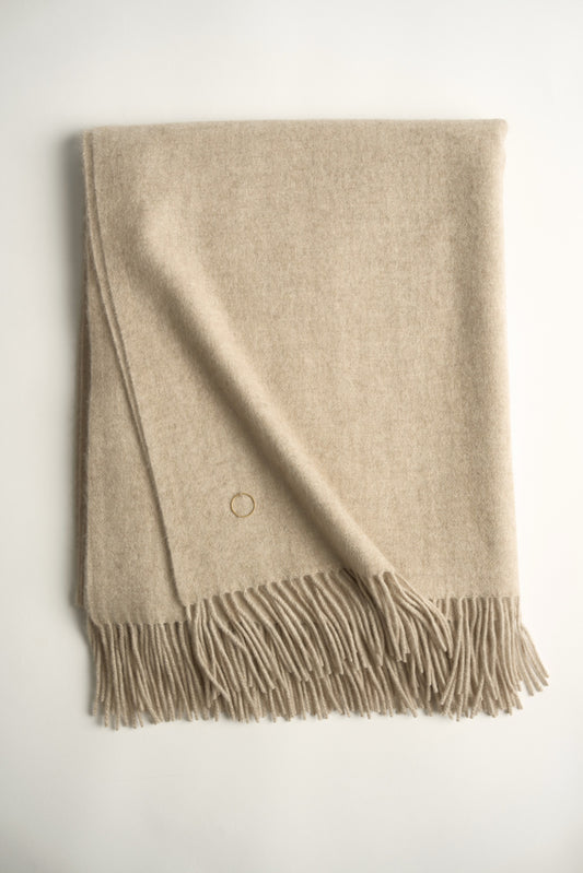 A beige cashmere throw with fringes at the top and bottom edges, displayed on a plain background.