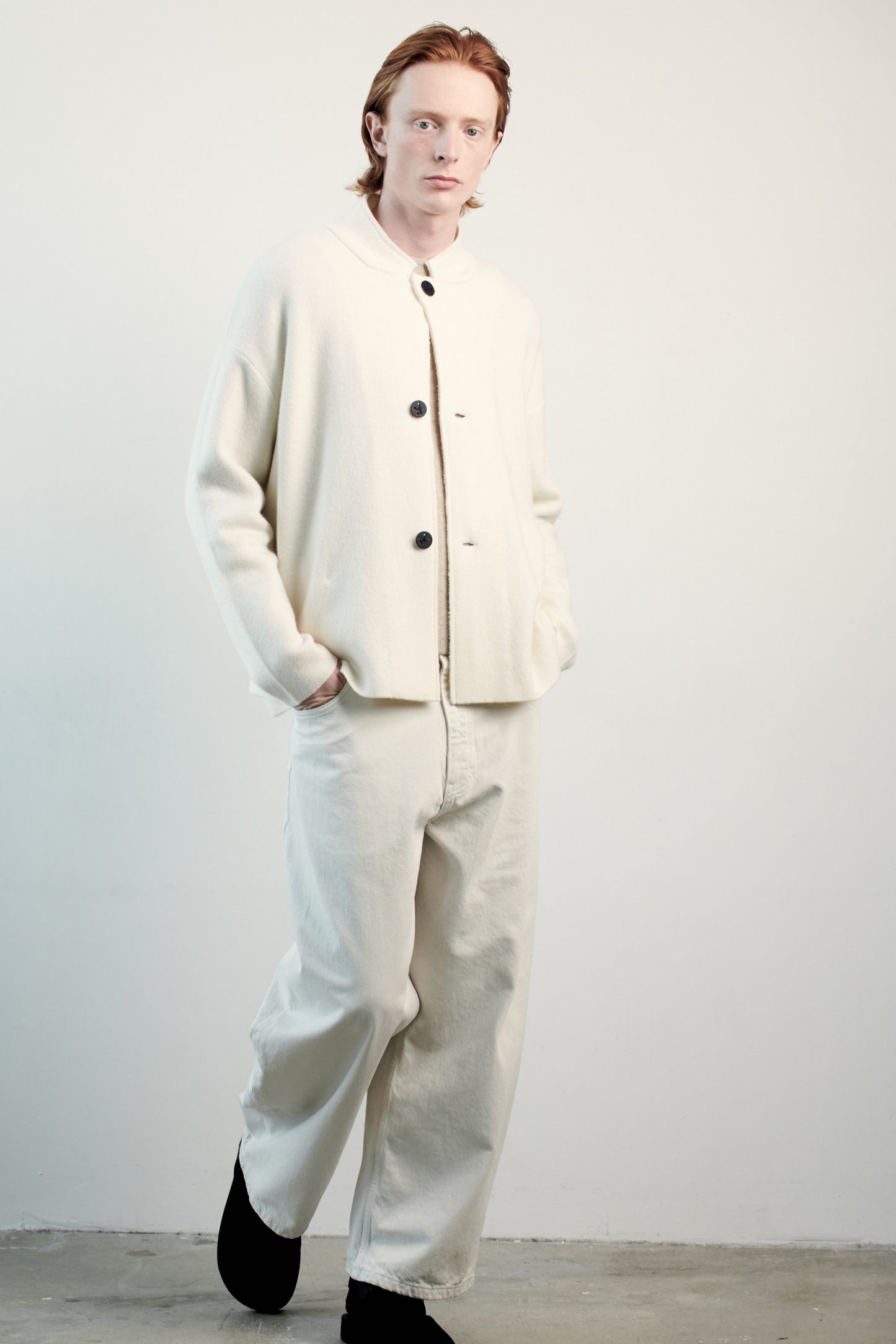 This image features a model wearing the Wind Jacket from Oyuna's core collection. The jacket is designed with a relaxed-fit and showcases a sophisticated look with its stand-up collar and welt pockets.