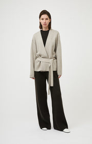 Person wearing Axomi wrap jacket in cashmere in colour Feather.  A relaxed fit jacket with statement sleeves and removable tie belt in cashmere. 