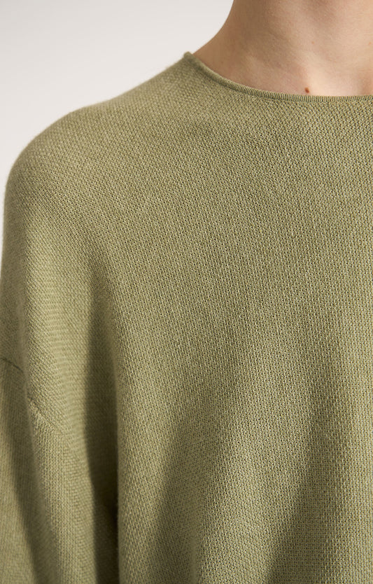 Woman wearing Lynco dropped shoulders cotton top in colour Fern. 