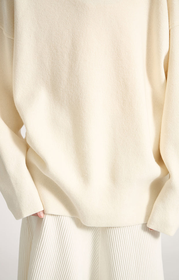 Woman wearing Seku knitted oversized cashmere hoodie in colour Ivory.
