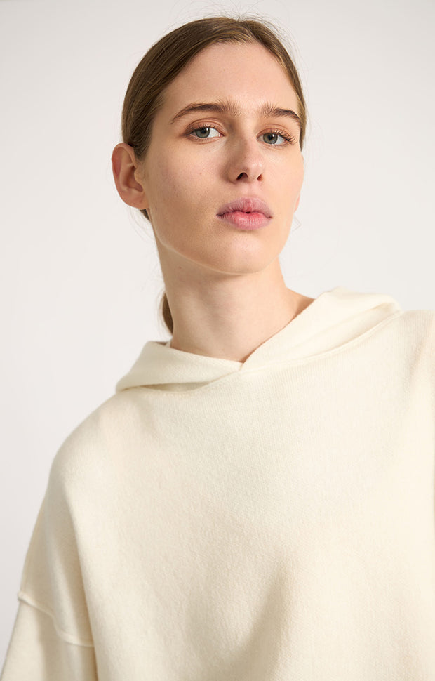 Woman wearing Seku knitted oversized cashmere hoodie in colour Ivory.