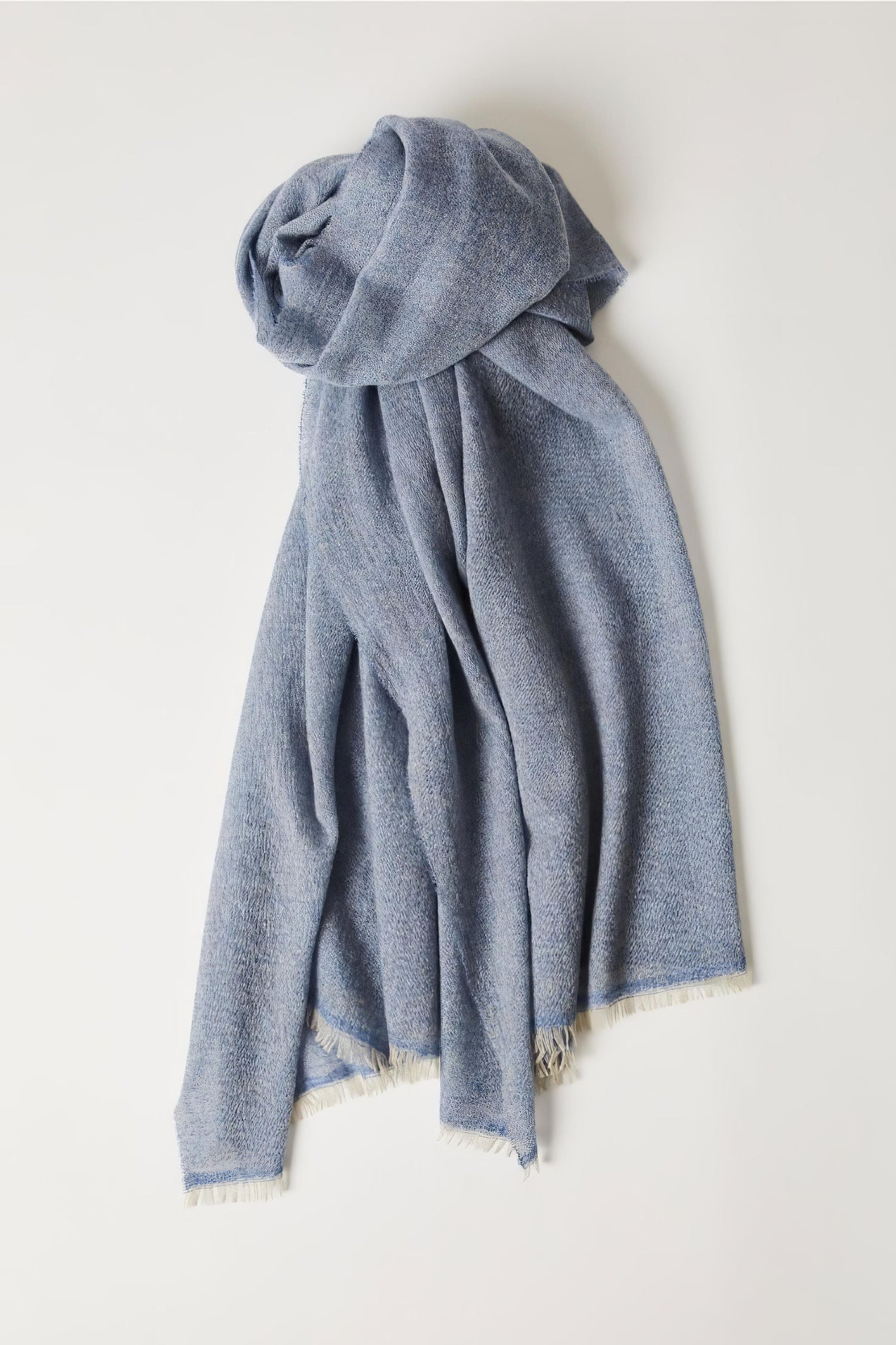 This image displays the Sera Shawl, a luxurious and elegant accessory crafted from the finest cashmere. The shawl features a subtle two-tone effect, achieved through a combination of different colors on the warp and weft, which enhances its sophisticated appeal.