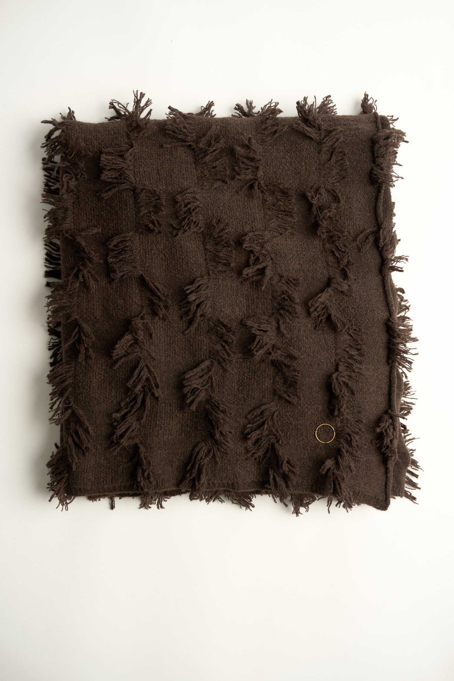 This image displays the Seren Throw, a luxurious cashmere knitted throw featuring a distinctive hand-cut fringe detail. The throw is presented in a deep, rich brown color, enhancing its elegant and sophisticated appearance.