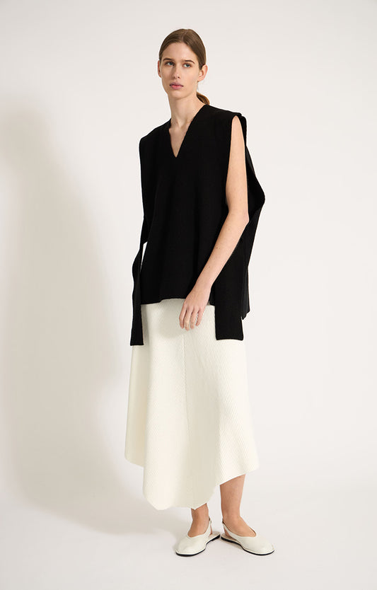 Woman wearing sleeveless cashmere top in colour Black. 