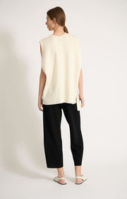 Woman wearing sleeveless cashmere top in colour Ivory. 