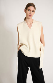 Woman wearing sleeveless cashmere top in colour Ivory. 